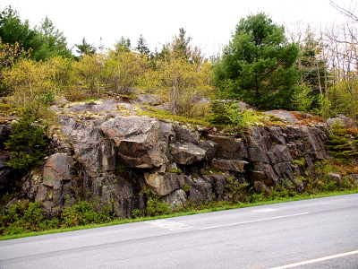 [Jagged rocks jutting from a hillside with more vegetation than the prior photo. These rocks look more likely to come off the hillside than the ones in the prior photo.]